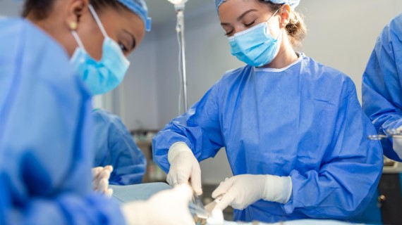An image of perioperative nurses in blue outfits in an operating room.