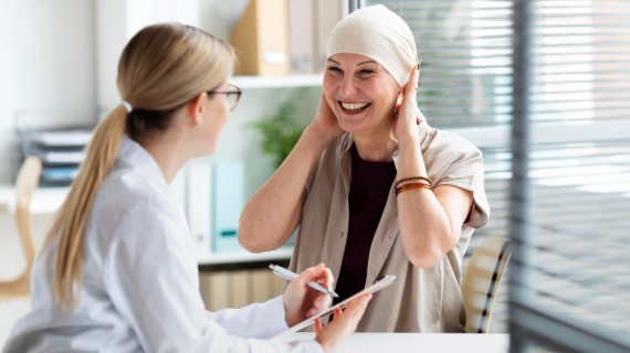An image of a smiling person with a bandana talking to a doctor.